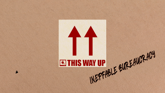 A cardboard box with a ‘this way up’ label and ‘ineffable bureaucracy’ scribbled on it. A fly is flying around in front of it.